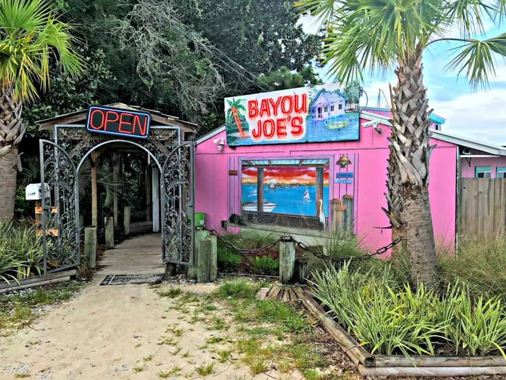 a pink building with a sign that says bayou joe's next to palm trees