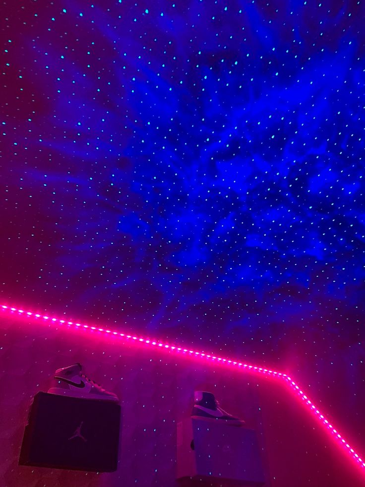 the ceiling is lit up with purple and blue lights, while two suitcases sit in front of them