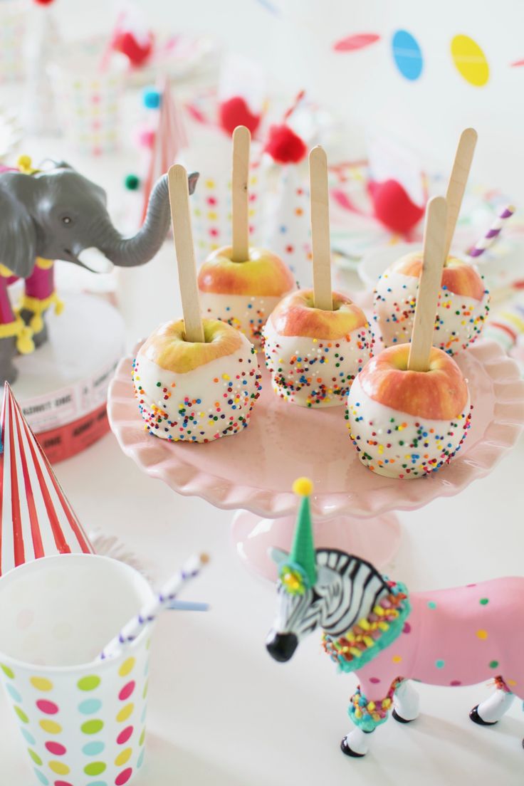 there are many donuts with sprinkles on the plate and an elephant figurine next to them