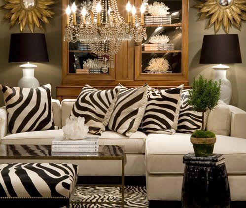 a living room with zebra print pillows and lamps on the wall above the couches