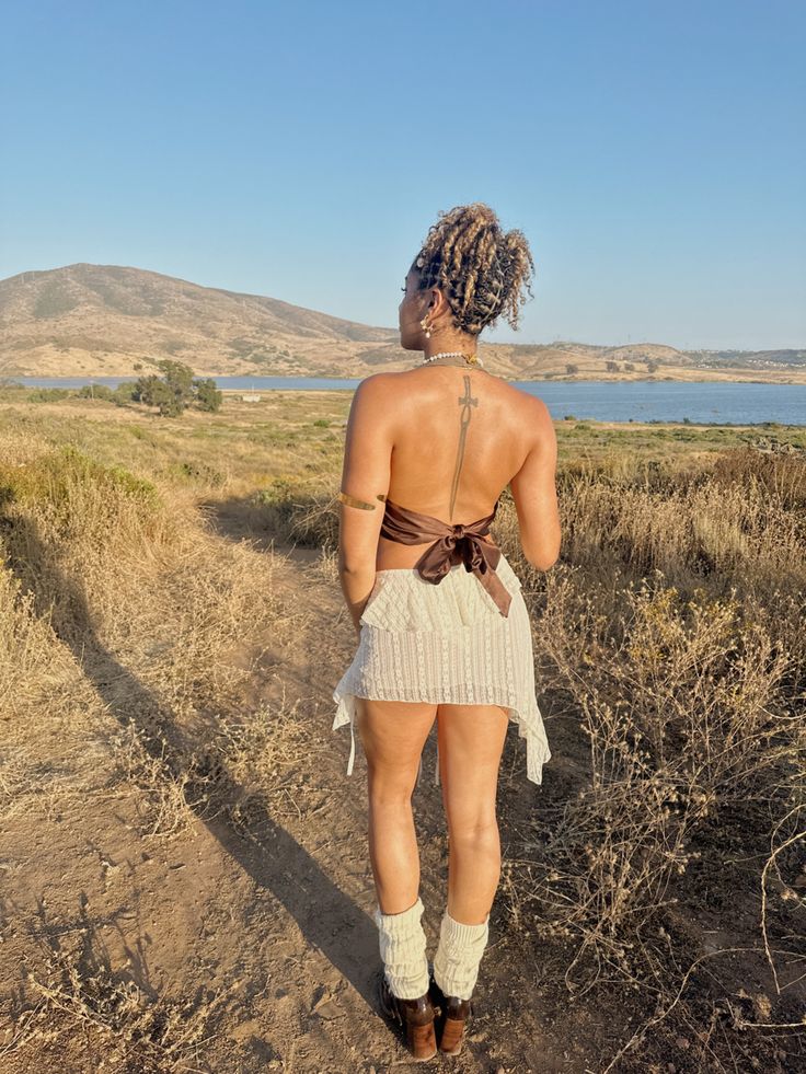 a woman walking down a dirt road next to a body of water