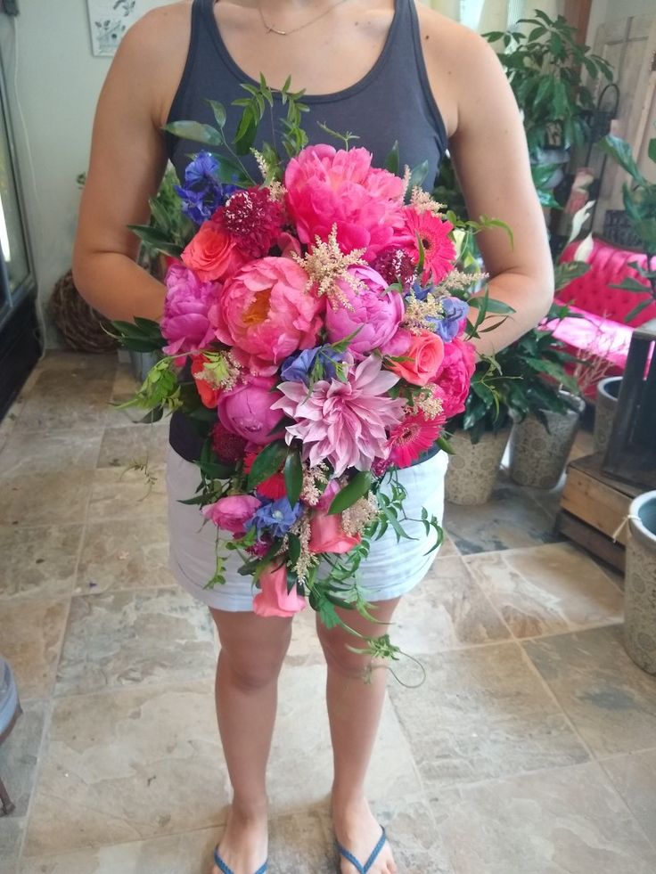 a woman holding a large bouquet of flowers in her hands while standing on a tile floor