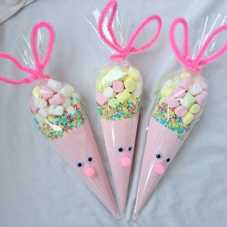 three candy cones with candies in them and bunny ears on the top one is filled with sprinkles