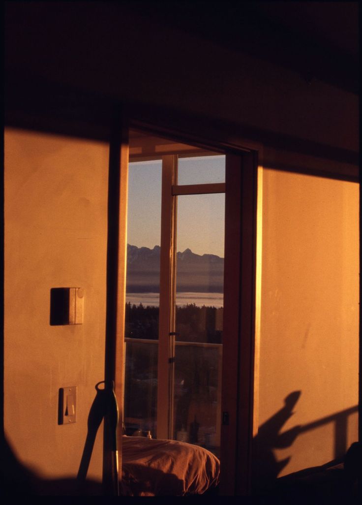 an open door leading to a balcony with a view of mountains and the ocean in the distance