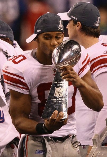 two football players are holding the trophy in front of their faces and looking at each other