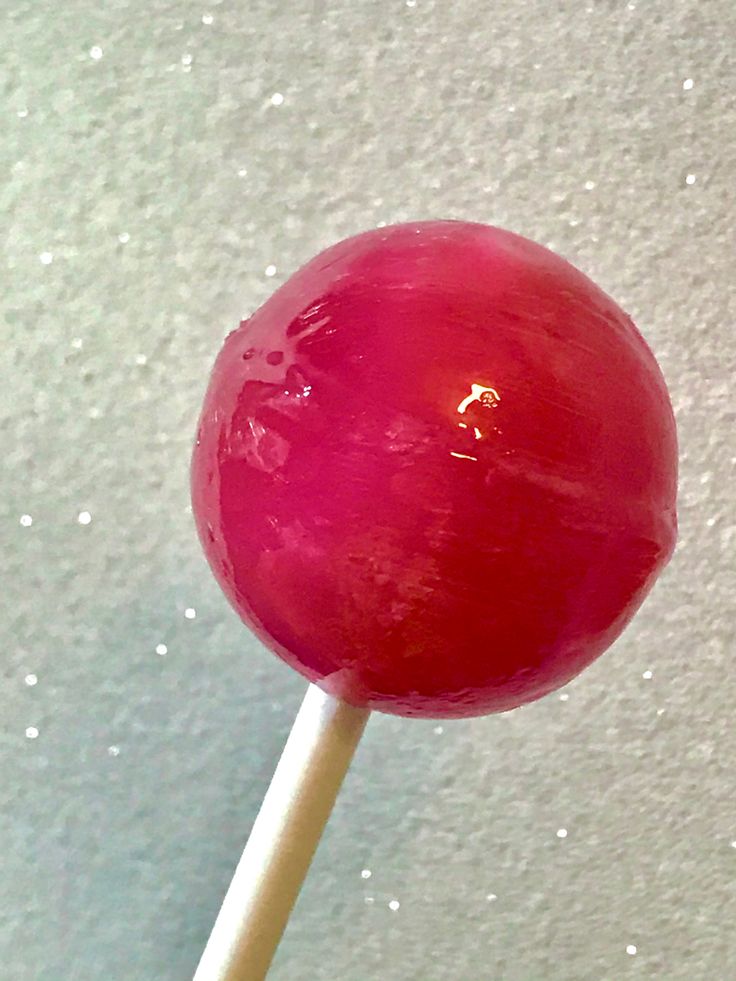 a red lollipop sitting on top of a wooden stick