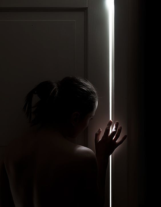 a woman standing in front of a door holding onto a light