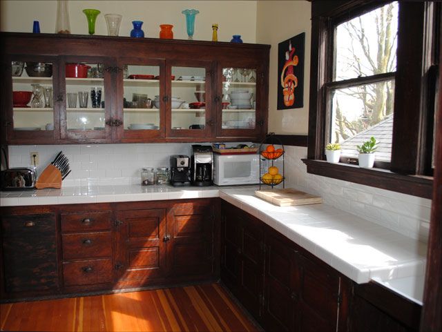 a kitchen with wooden cabinets and white counter tops next to a wood flooring area