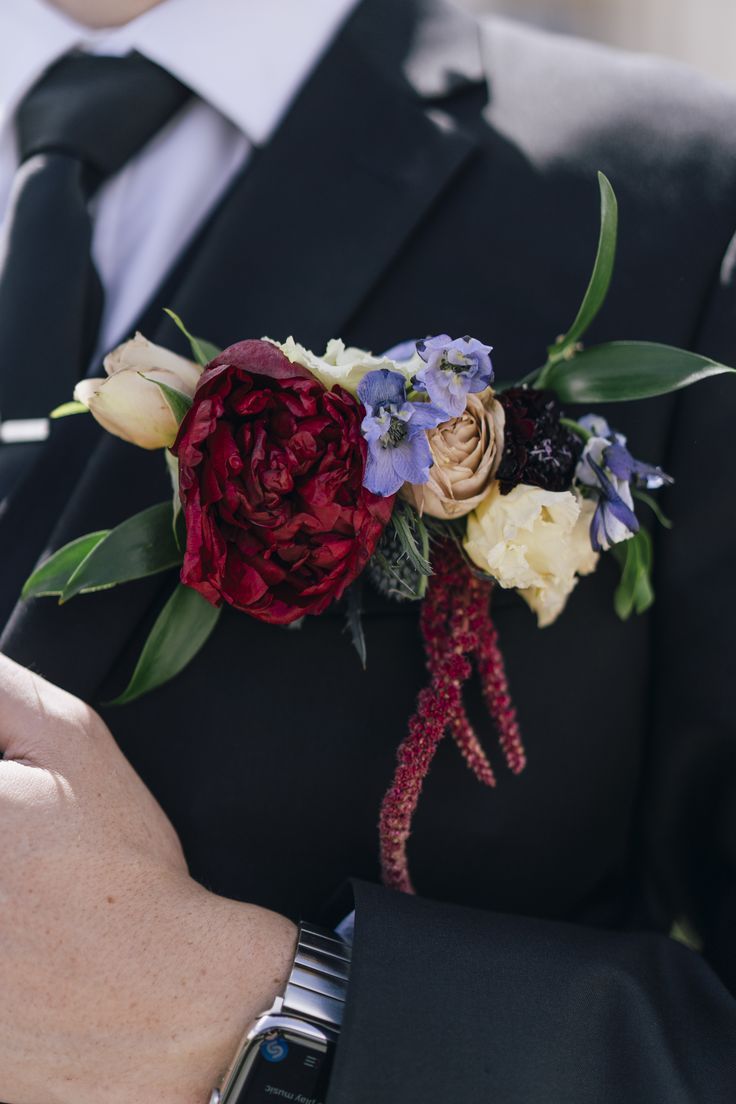 a close up of a person wearing a suit and tie with flowers on his lapel