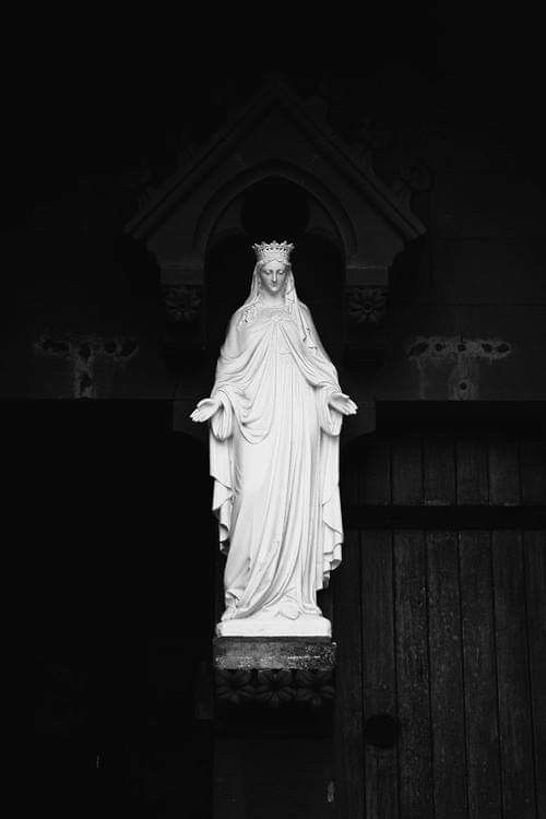 black and white photograph of the statue of jesus in front of a church entrance door