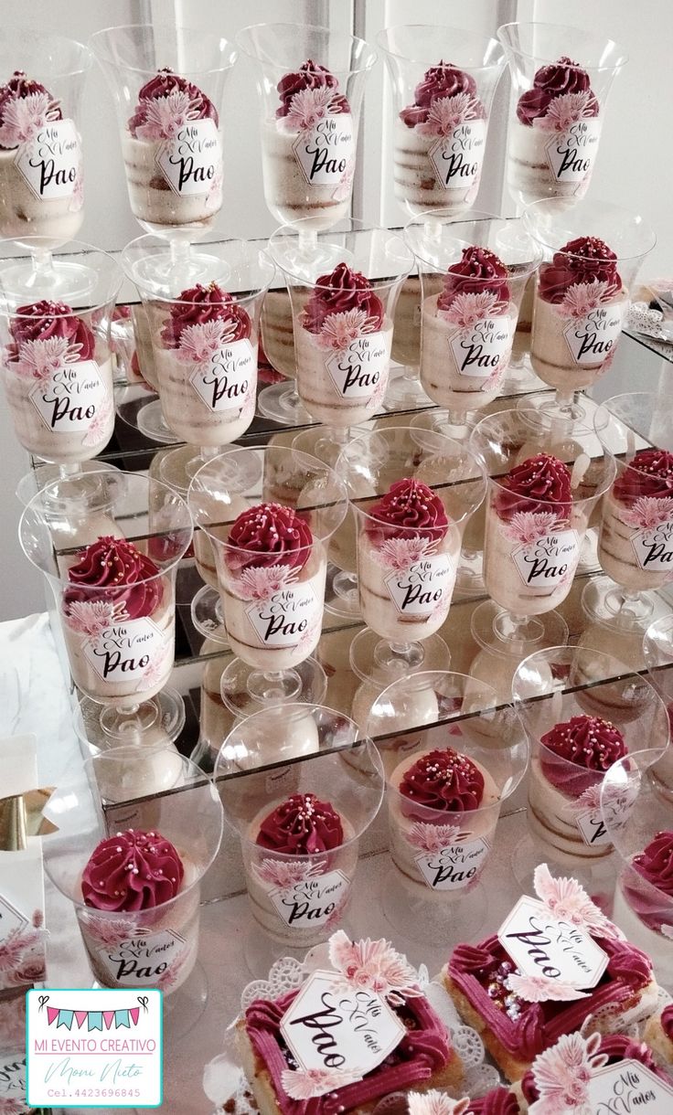 there are many small cupcakes on display in the glass case with tags attached to them