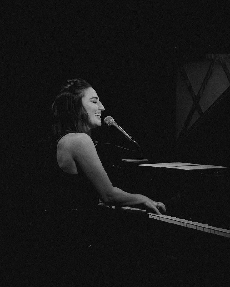 a woman sitting at a piano in front of a microphone and singing into a microphone