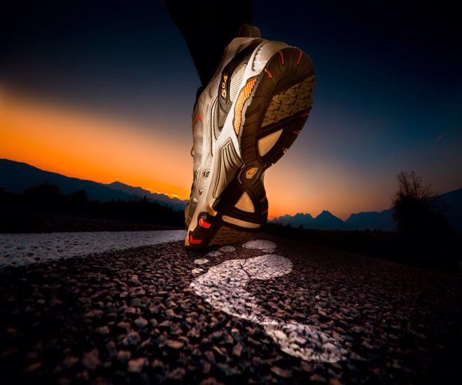 a person's feet with their shoes on the ground at sunset or dawn,