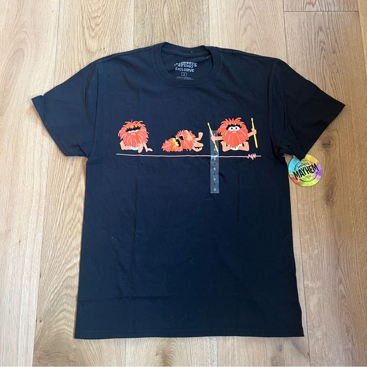 a t - shirt with an image of the muppets on it is laying on a wooden floor