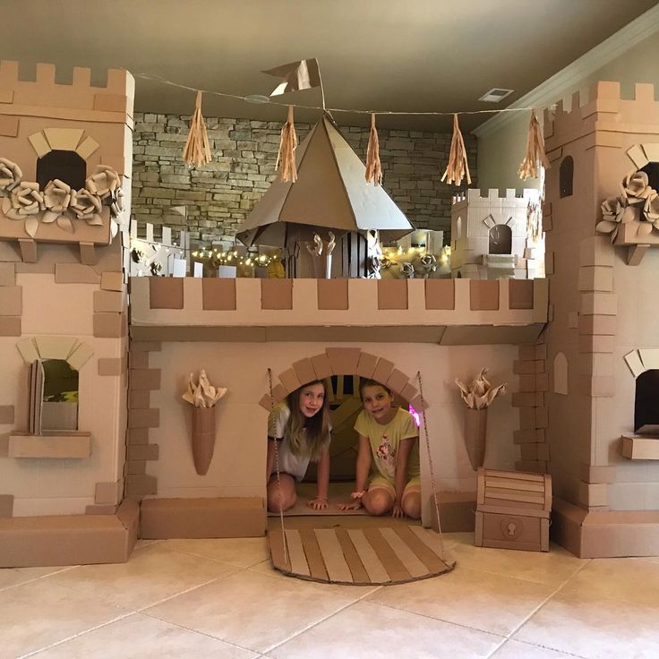 two girls are playing in a cardboard castle