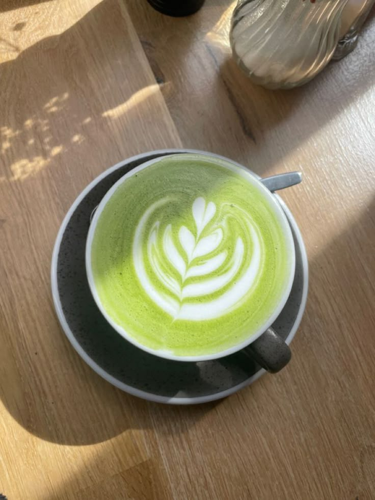 a cup of green tea on top of a wooden table