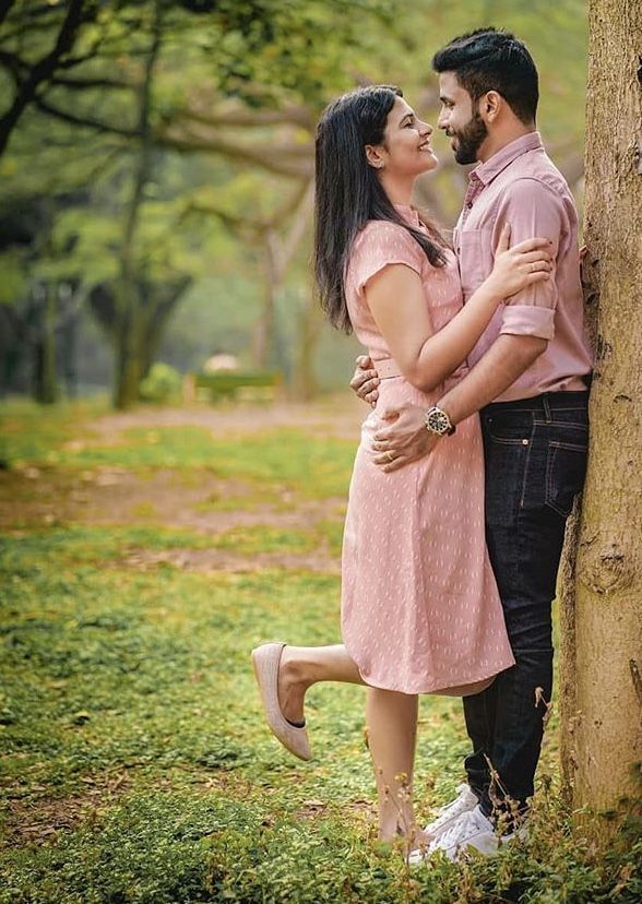 a man and woman standing next to each other near a tree