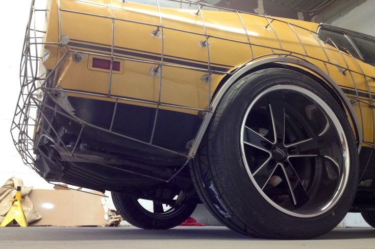 a yellow car is being worked on in a garage with some tools around it and the tire rims are missing