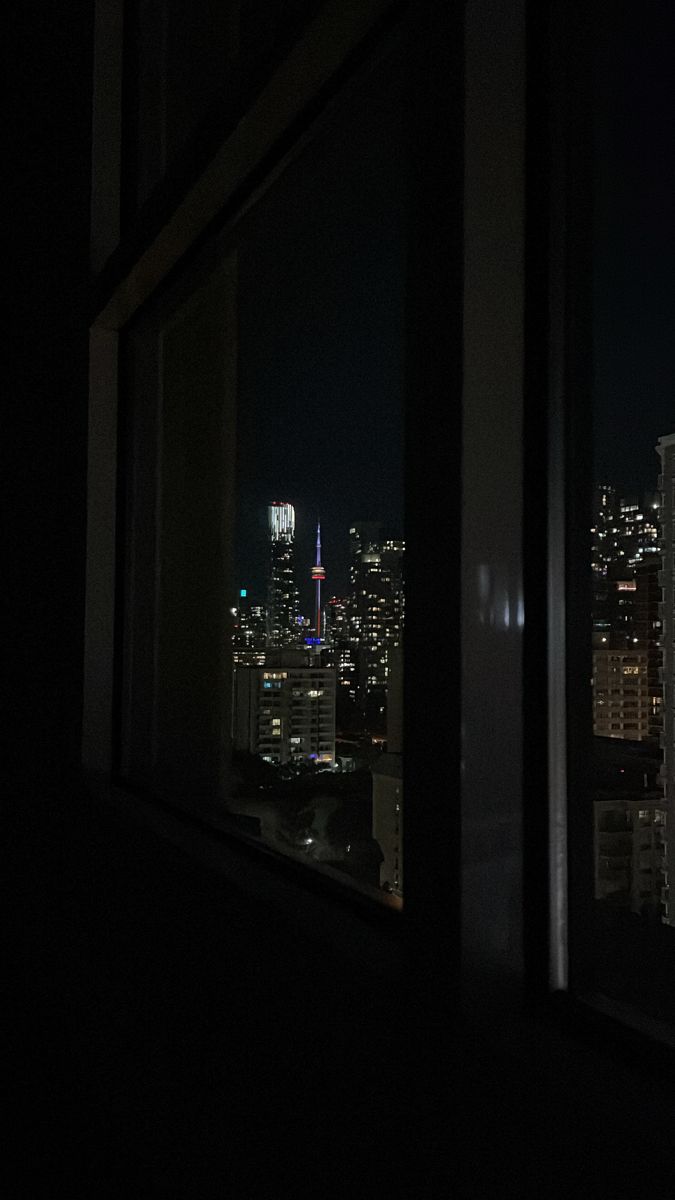 the city lights are lit up at night from an apartment window in new york's financial district