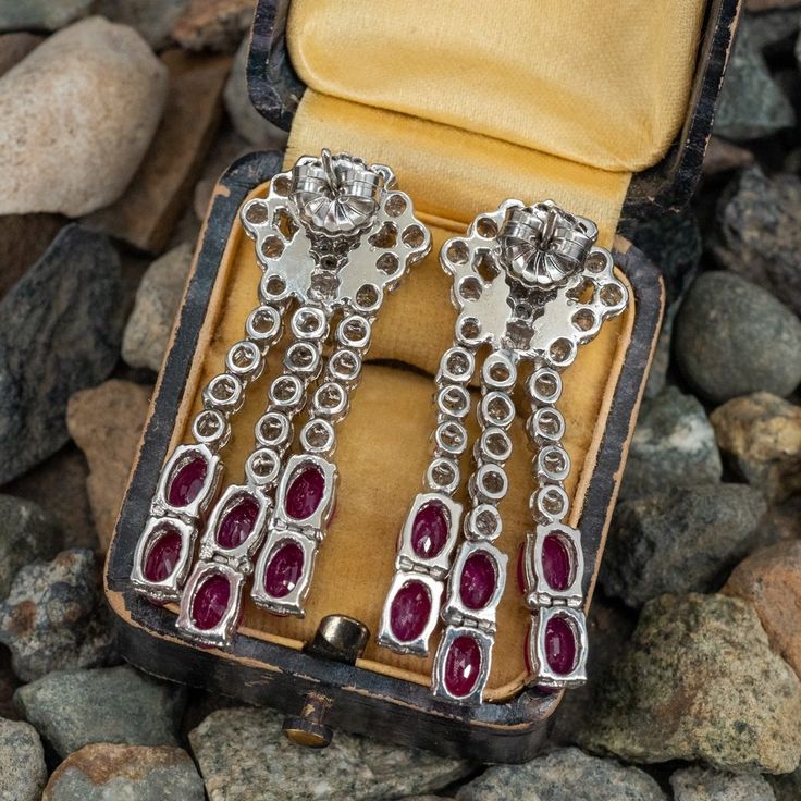 These lovely dangle style pierced earrings are each accented with three (3), prong set, baguette cut diamonds, thirty-three (33), prong set, round brilliant cut diamonds and six (6), prong set, oval mixed cut natural rubies. The earrings measure 42mm X 15mm and are finished with friction style backs. Elegant Baguette Cut Single Diamond Earrings, Platinum Baguette Diamond Earrings For Wedding, Baguette Cut Diamond Earrings With Prong Setting, Wedding Platinum Earrings With Baguette Diamonds, Baguette Cut Diamond Earrings For Formal Events, Baguette Cut Diamond Earrings For Formal Occasions, Art Deco Diamond Earrings With Brilliant Cut, Evening Baguette Diamond Dangle Earrings, Anniversary Baguette Diamond Drop Earrings