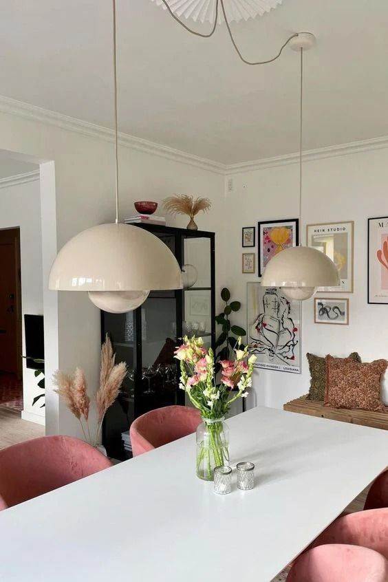 a white table with pink chairs and pictures on the wall