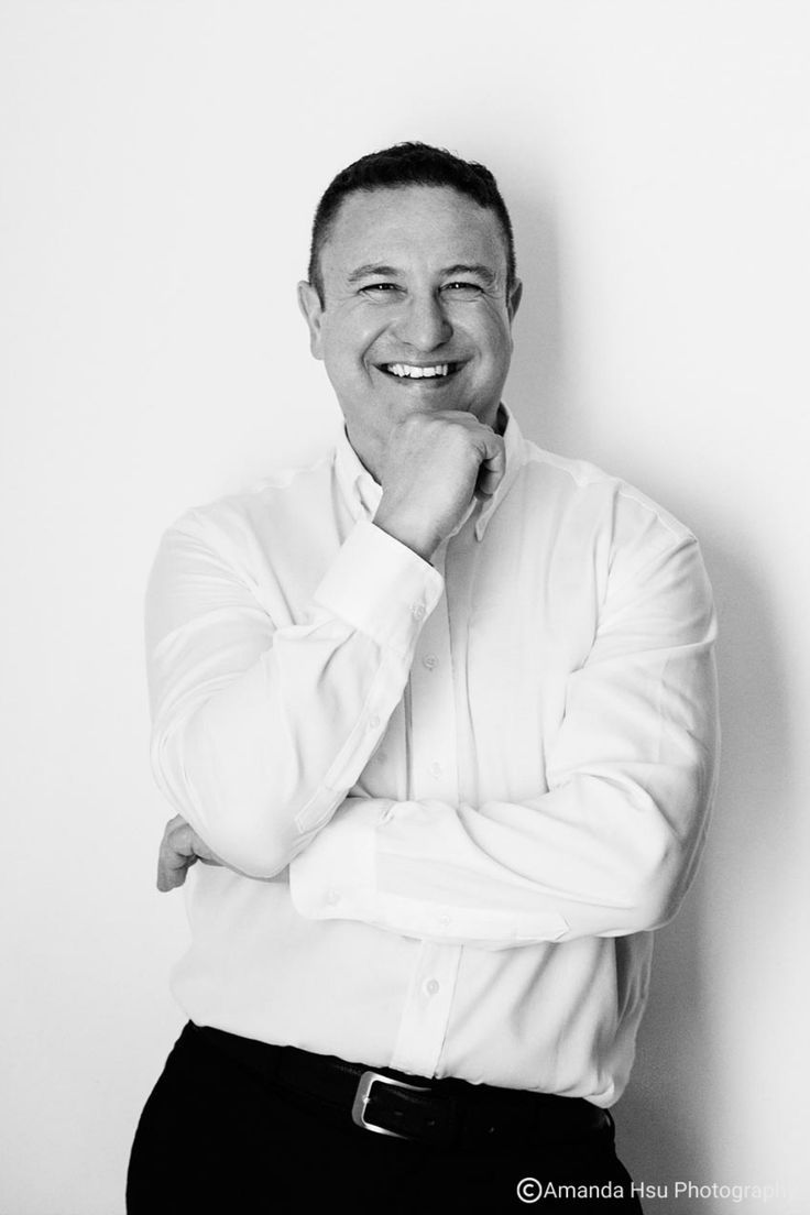 a black and white photo of a smiling man with his chin resting on his hand