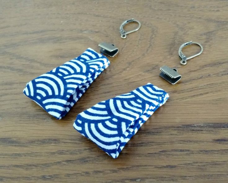 two pieces of paper sitting on top of a wooden table next to metal clips and hooks