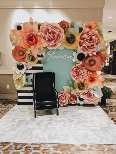 a black chair sitting in front of a floral wall