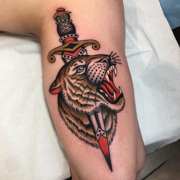 a tattoo on the leg of a person with a wolf wearing a hat and dagger