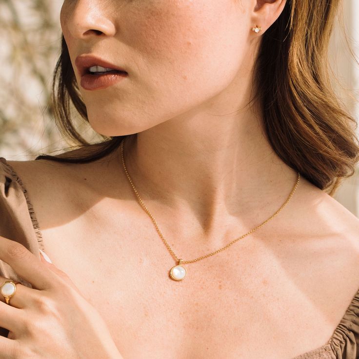 Introducing the Anna Pendant - a stunning, handmade piece of jewelry crafted with gorgeous Mother of Pearl and finished with a delicate gold rolo chain. This unique pendant is sure to be your favorite go-to accessory, adding just the right amount of glimmer and style to any outfit. Don't you deserve to feel luxurious and beautiful? Available in 14k gold plated brass 10mm Mother of Pearl Cabochon 18" rolo chain with 2" extender Lobster claw closure SKU: BYN1375 Feminine Gold Charm Necklaces For Gifts, Dainty Oval Pendant Jewelry With Adjustable Chain, Timeless Gold Plated Jewelry With Pearl Pendant, Feminine Gold Charm Necklace For Gift, Delicate Clavicle Jewelry With Oval Pendant, Timeless White Gold Plated Necklaces, Delicate Oval Pendant Clavicle Chain Jewelry, Oval Pendant Jewelry With Delicate Chain For Gifts, Oval Pendant Jewelry With Delicate Chain As Gift