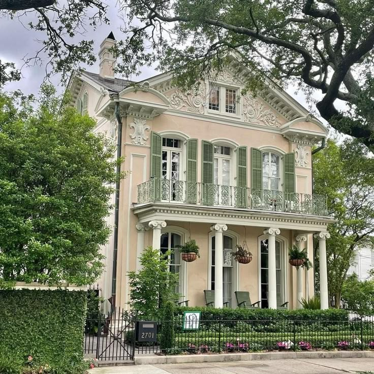 a pink house with green shutters and trees