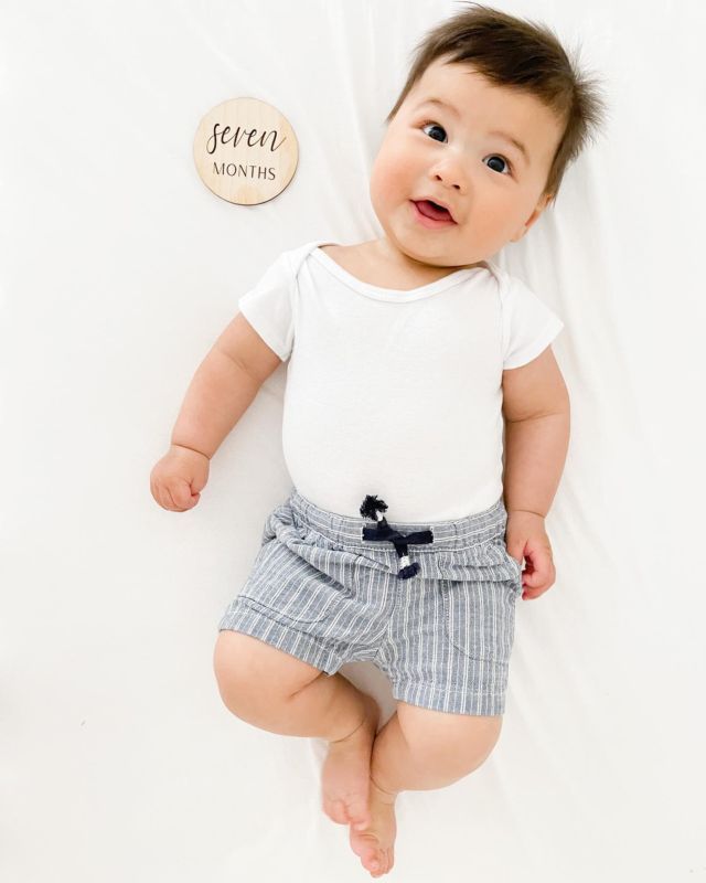 a baby is laying on the floor wearing shorts