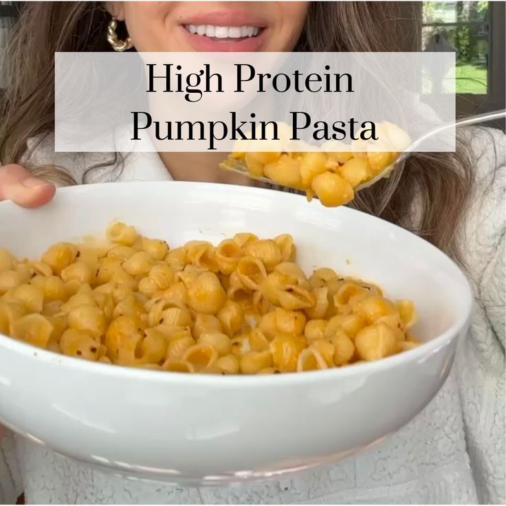 a woman holding a white bowl filled with macaroni and cheese