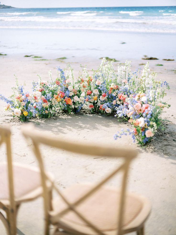 an arrangement of wildflowers and other flowers on the beach