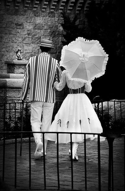 a man and woman walking down the street holding umbrellas