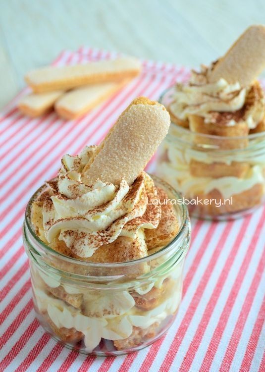 two jars filled with desserts sitting on top of a red and white table cloth