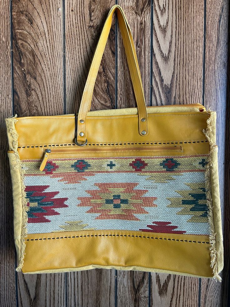 The distinctive style of this amazing bag is beautiful. From the combination of sunrise yellow leather, tribal-inspired upcycled rug and frayed edge accents, to the roomy interior with zipper-close top, it makes for a purely great life accessory! The back and sides are in a coordinate woven canvas. Both the front and back have zippered pockets for added convenience. Study carrying straps are in matching leather. You'll love the appeal and great service of this gorgeous bag! Dimensions: 20" X 8" X 16" *All sales final Mustard Tote Shoulder Bag For Travel, Bohemian Shoulder Bag With Leather Trim For Everyday Use, Everyday Bohemian Shoulder Bag With Zipper Closure, Everyday Bohemian Shoulder Bag With Zipper, Bohemian Yellow Shoulder Bag For Travel, Yellow Bohemian Shoulder Bag For Travel, Artisan Yellow Bag For Everyday Use, Bohemian Bags With Leather Trim, Yellow Artisan Bags For Daily Use