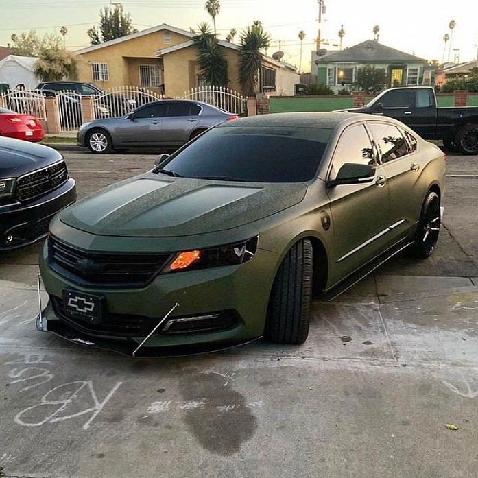 a green car parked in a parking lot next to other cars