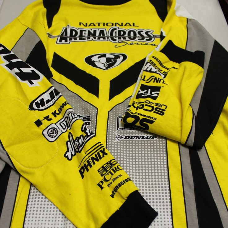 a yellow jersey with black and grey details on it is laying on a white surface