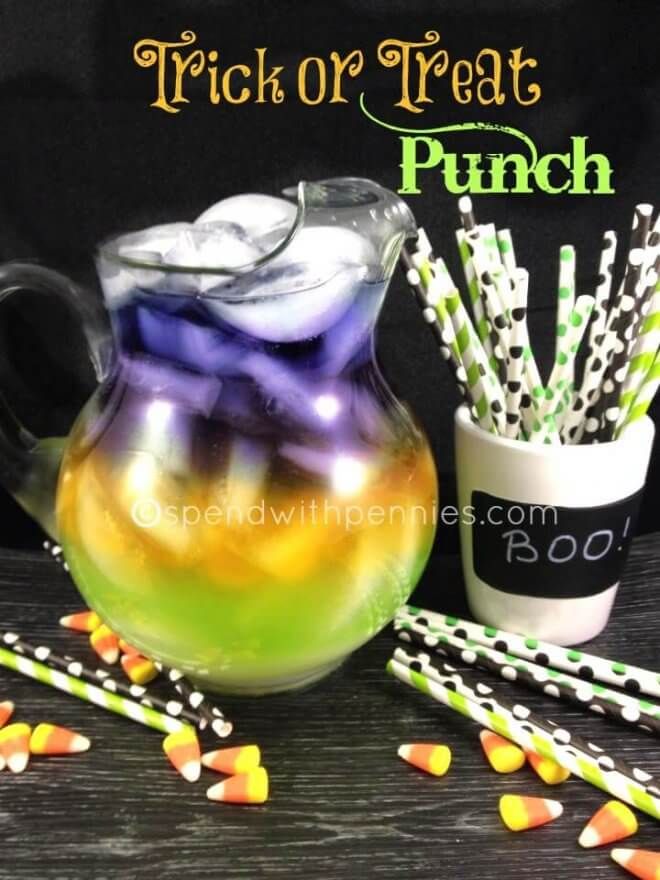 a pitcher filled with candy sitting on top of a table next to some straws