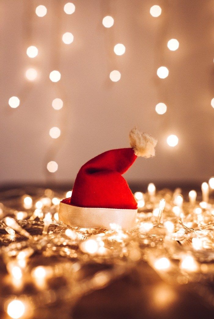 a red and white santa hat sitting on top of a pile of gold tinsel