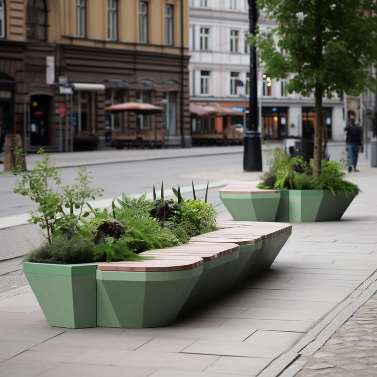 two green planters with plants in them sitting on the side of a road next to buildings