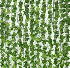 green ivy growing on the side of a white wall in front of a window with vertical blinds