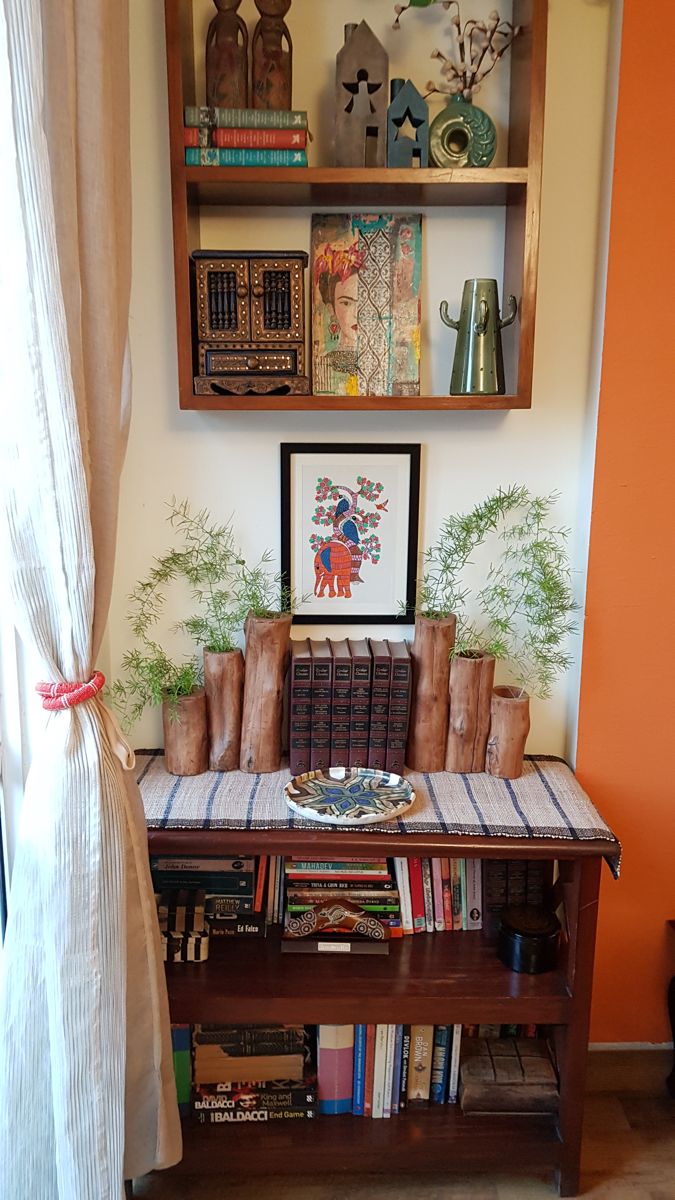 a table with books and vases on it in front of a book shelf filled with books