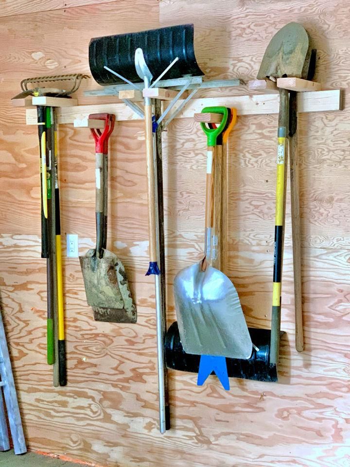 there are many different tools hanging on the wall in this room, including shovels and gardening implements