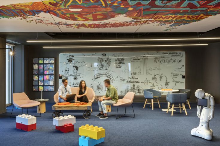 three people sitting in a room with legos on the floor and graffiti painted on the walls