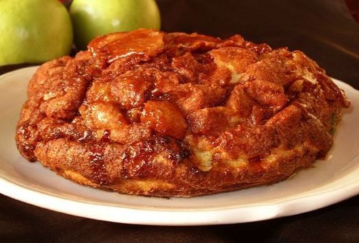 an apple pie on a white plate next to two green apples