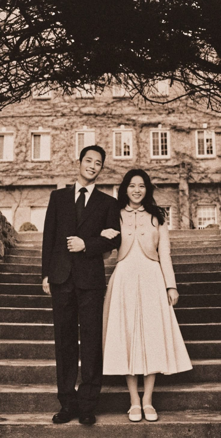 a man and woman standing on steps in front of an old building with stairs leading up to them