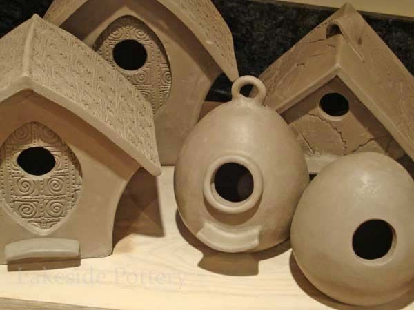 four ceramic bird houses with holes in them