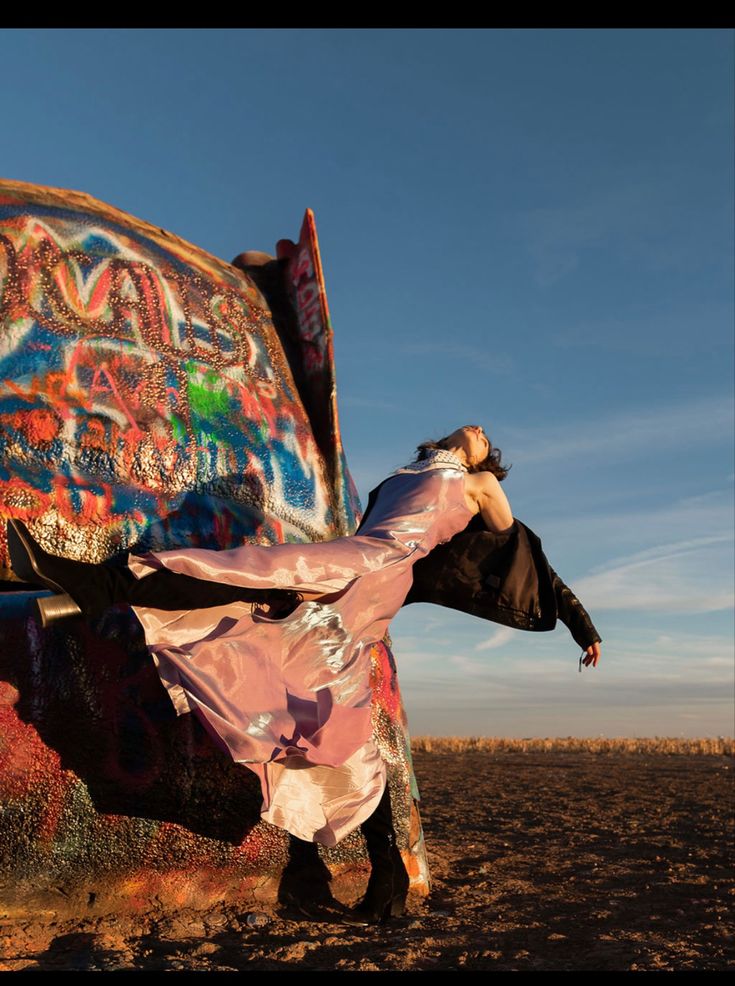 a woman is leaning against a large piece of art